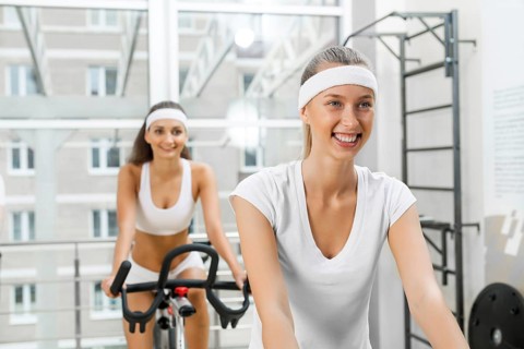 Small group of young people exercising on bikes in fitness center