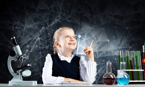 Little girl scientist sitting at desk in elementary science class. Research and education in school