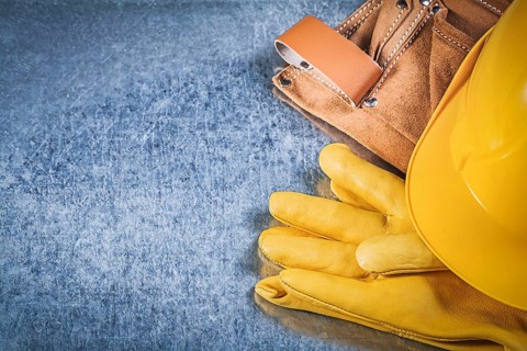 Safety gloves tool belt hard hat on metallic background construction concept
