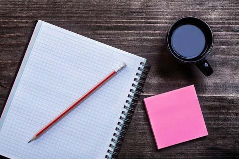 Open notepad pencil reminder note and cup of coffee on wooden board office concept