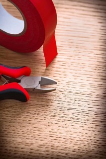 Vertical view nippers with insulating tape on wooden board
