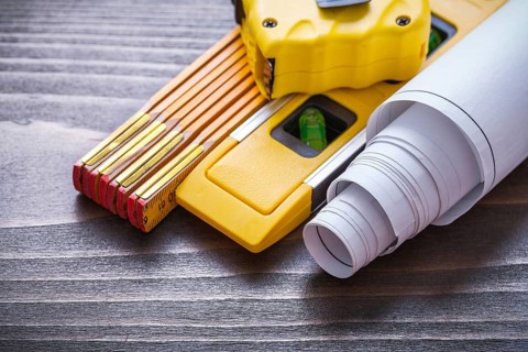 Tape-measure blueprints construction level and wooden meter on vintage wood board close up image