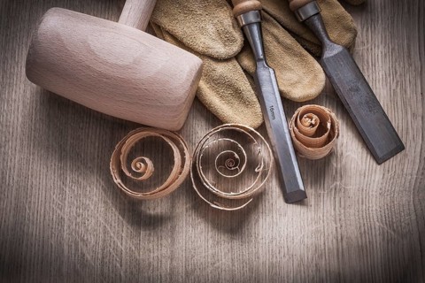 Wooden mallet curled up shavings firmer chisels leather gloves on wood board construction concept
