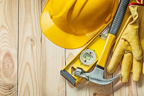Claw hammer construction level leather gloves and construction helmet on wood