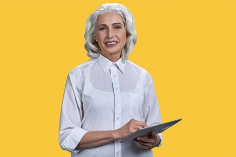 Smiling mature business woman holding pc tablet and looking at camera. Beautiful elderly woman with