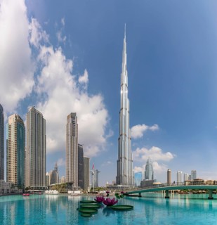 A picture of the Burj Khalifa towering the nearby Downtown Dubai buildings and the blue waters of