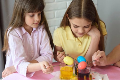 Children stain eggs in a special dye in glasses