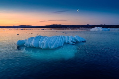 Floating glaciers in the rays of the setting sun at polar night with Moon