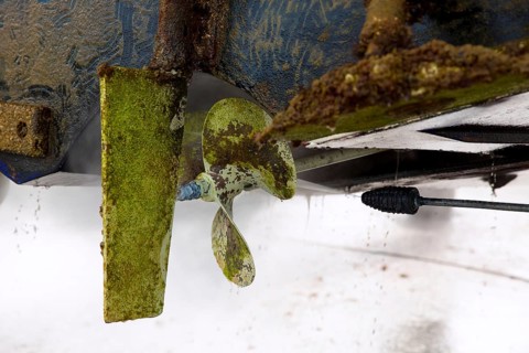 Boat stern hull and propeller pressure water cleaning on beached ship