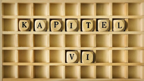 An image of a wooden game with the word chapter six in german language