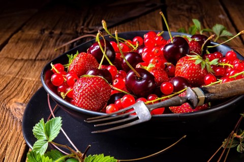 Bowl with different fruits such as strawberry, red currant, and cherry