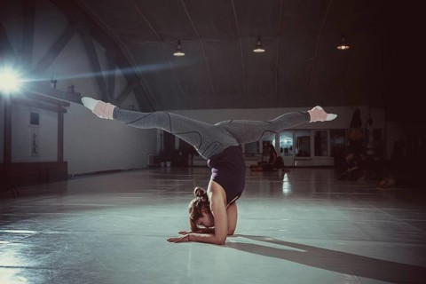 Young attractive yogi woman practicing yoga concept, standing in variation of Pincha Mayurasana