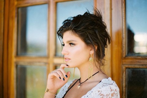 Woman touches her chin with her fingers against the backdrop of a glass door. Close-up.