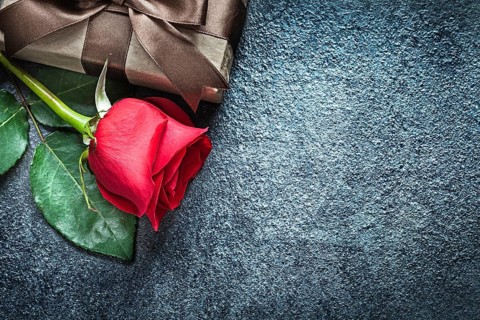 Gift box with brown ribbon red rose on black background holidays concept