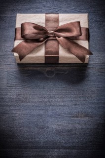 Gift box-container in wrapping paper on vintage wooden board