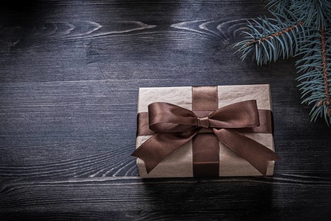 Pine branch wrapped gift box on wooden board holiday concept