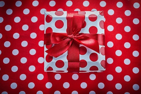 White present box with tied ribbon on polka-dot red fabric celebrations concept