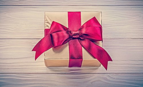 Wrapped present box on wooden board directly above holidays concept