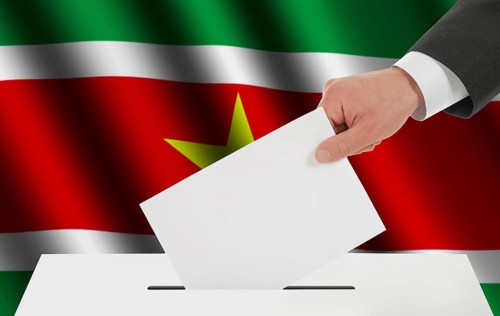 The Surinam flag and the hand with the bulletin about the ballot box