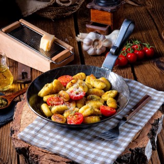 Gnocchi baked with green pesto, cherry tomatoes and parmesan
