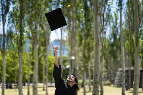 Graduated man throwing graduation hat in the air