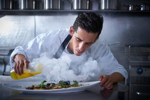 Chef working in kitchen with smoke and oil at restaurant
