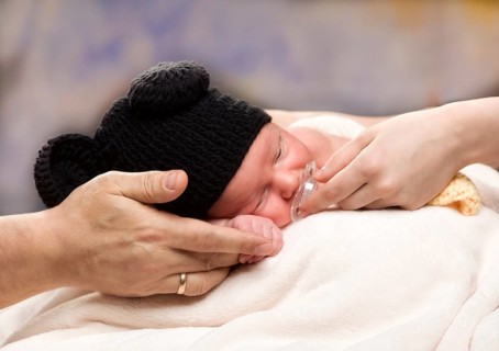 Newborn Baby Boy Sleeping on Parents Hands, over coloured background