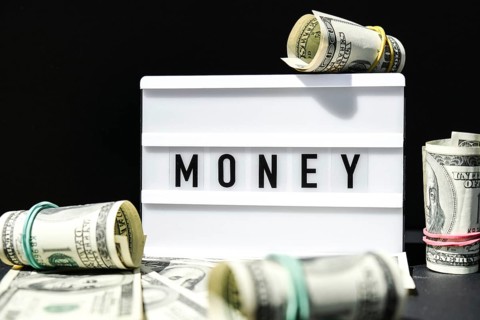 Lightbox board with the word MONEY in black letters around Us dollars banknotes. Finance background
