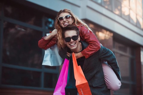 Happy couple shopping together and having fun. Boyfriend carrying his girlfriend on the piggyback