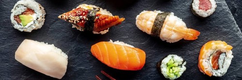 Sushi overhead flat lay panorama. Rolls, maki, nigiri on a black background, Japanese food. Salmon,