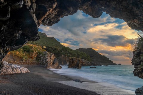 Silhouette frame of a beach cave and view Marina di Maratea Beach at sunset