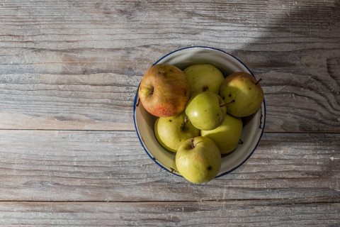 Apples in vintage metal cup on white wooden table