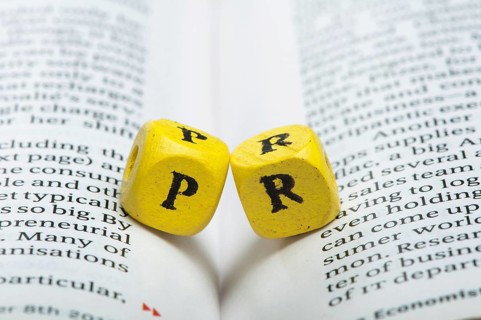 Word PR.Wooden cubes on newspaper. Close up studio shot