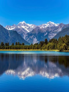 The forests and Mount Cook and Mount Tasman. Magnificent snow-capped mountains surround the smooth,