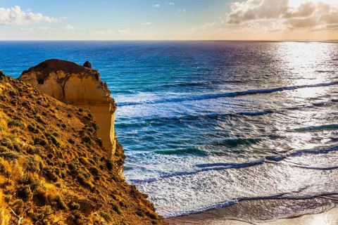 Powerful ocean surf at sunset. The Great Ocean Road. Steep and rocky ocean shore of Australia. The