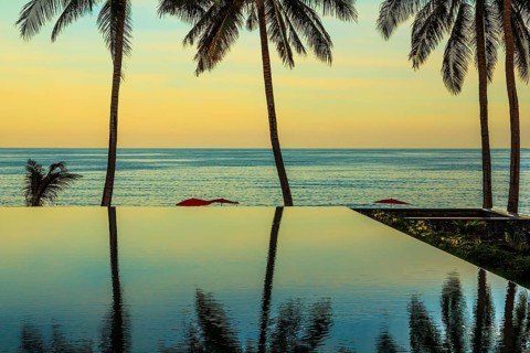 Delicate sunset on the popular resort island of Koh Samui. Palm trees reflected in smooth water of
