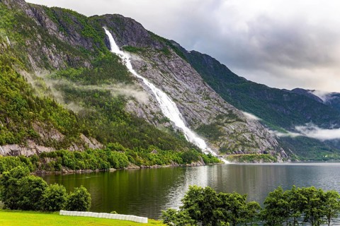 Magnificent giant picturesque Langfossen waterfall and flows into the Acre Fjord. Majestic natural