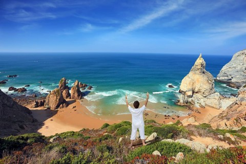Small beautiful beach on the Atlantic coast. Middle-aged woman dressed in white doing yoga. The