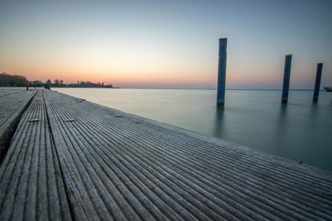 Sunrise on the shore and harbour of a lake in summer. Colourful sky with a wide view of the horiont