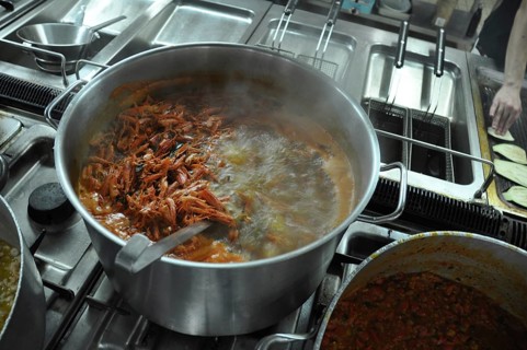Shrimp boiling in a large pot on a stove in a busy kitchen setting, Cooks and chefs prepare dinner
