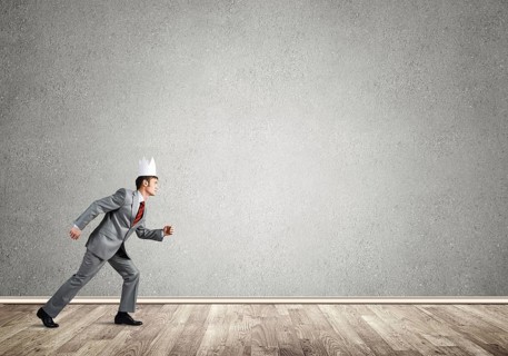 Young handsome businessman wearing white paper crown running in a hurry