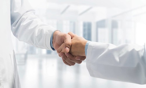 Close-up of the handshake between the two medics. Against the backdrop of the cityscape