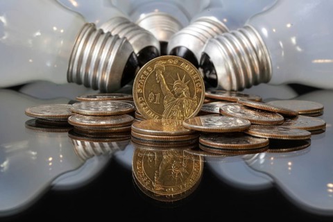 Wasteful bulbs and U.S. dollar coins on a black table