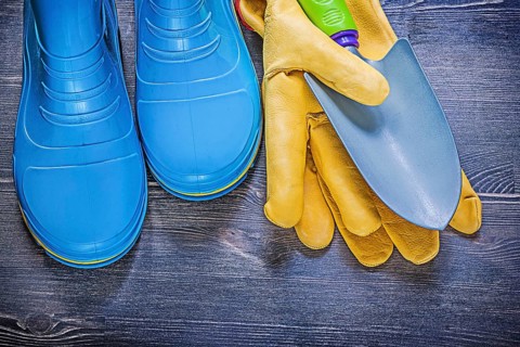 Leather safety gloves metal hand spade waterproof rubber boots on wooden board agriculture concept