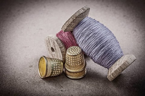 Spools of sewing threads thimbles on vintage background needlework concept