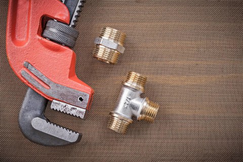 Pipe wrench brass plumbing fixtures on cleaning mesh filter grid