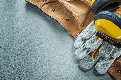 Set of leather tool belt safety gloves earmuffs on concrete background