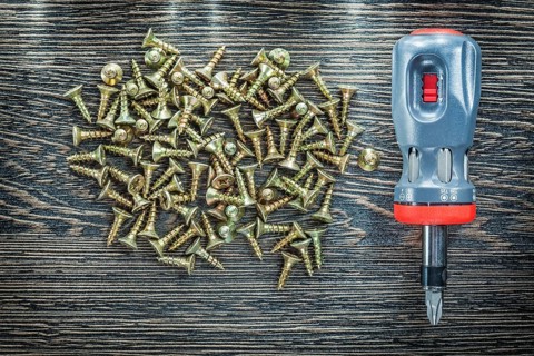 Screwdriver tapping screws on wooden board