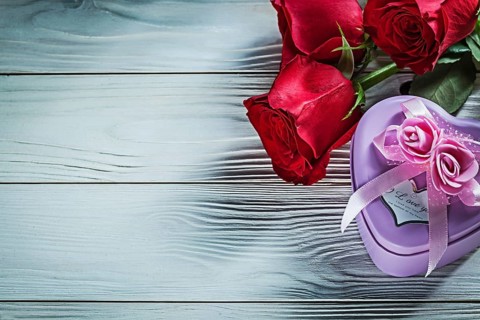 Metal heart-shaped gift box red roses on wooden board holidays concept