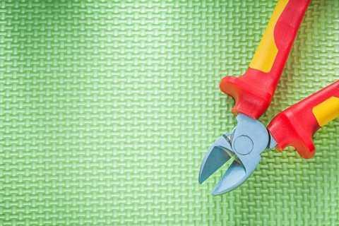 Sharp insulation nippers on green background electricity concept